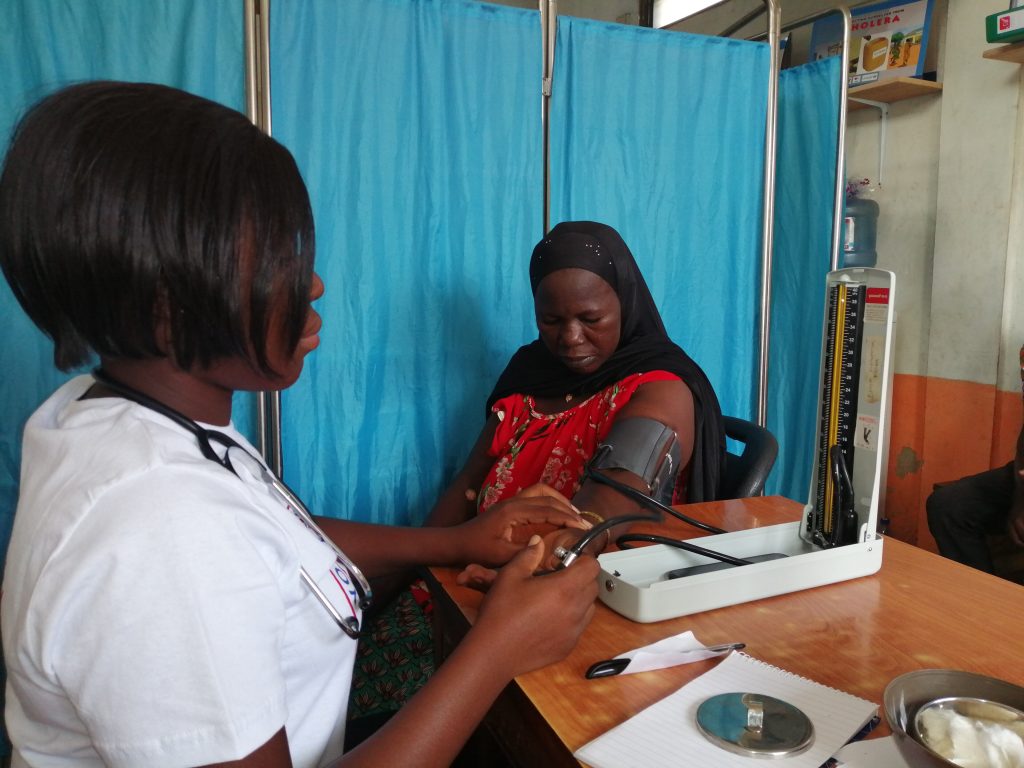 A health worker checks a woman's blood pressure at a clinic in Ghana